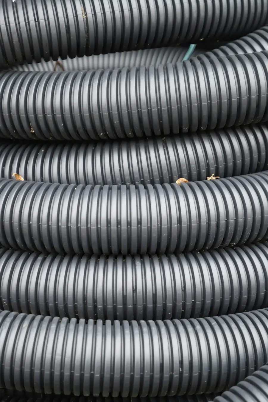 Coils of black corrugated drainage pipe stacked together