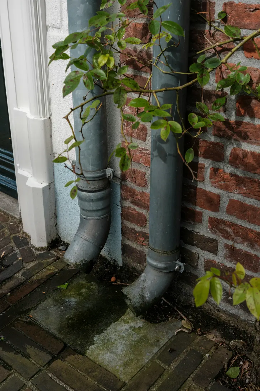 Downspout running down the corner of a brick house wall